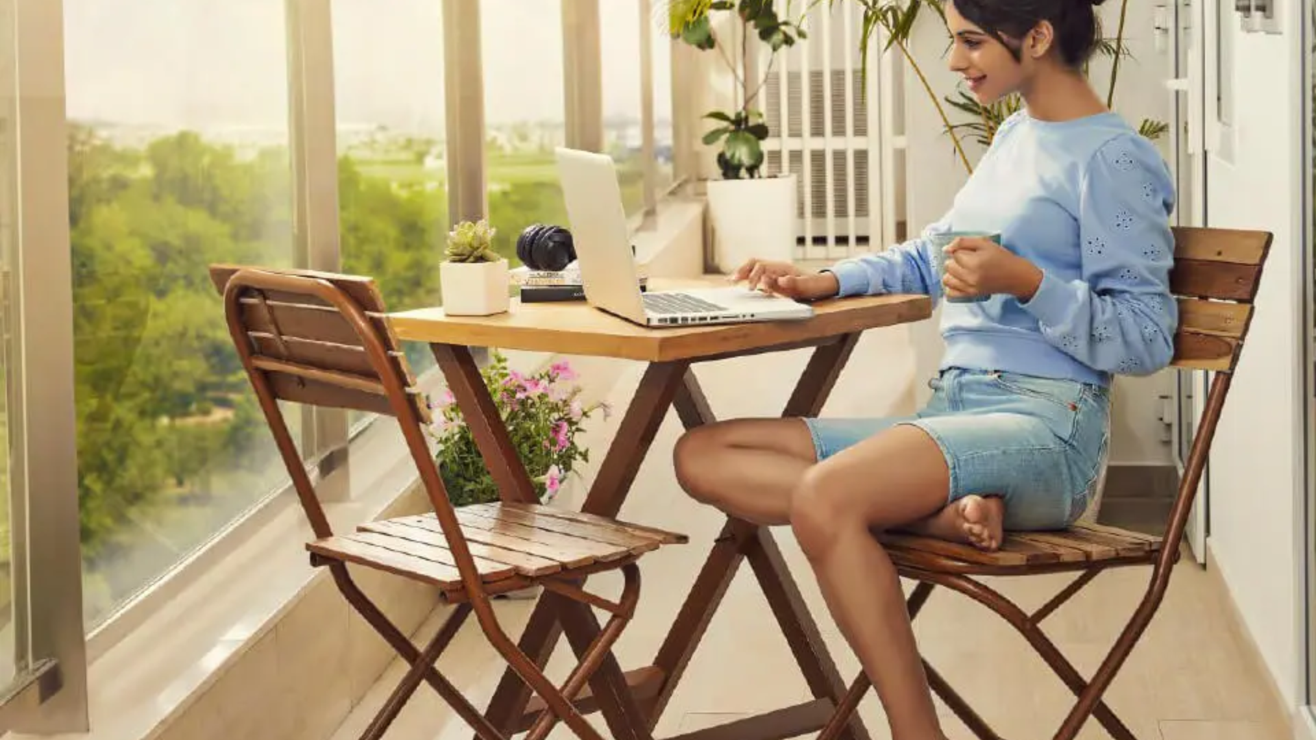 Woman relaxing in a luxury balcony seating area with modern outdoor furniture and greenery.